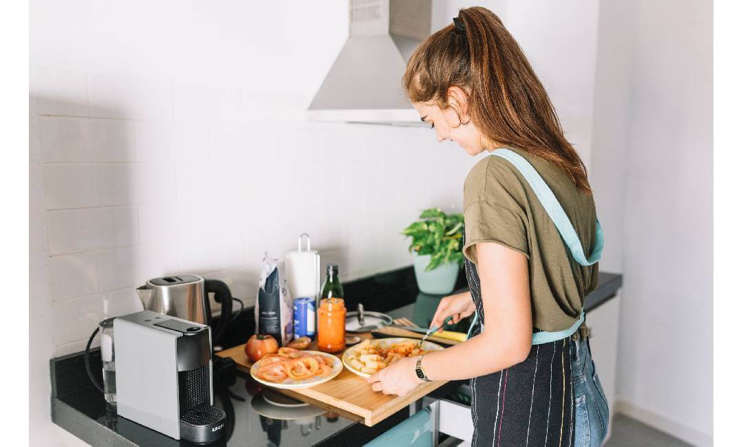 Woman cooking and preparing food on a cutting board in a modern home kitchen