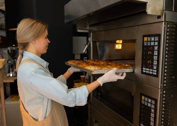 Chef placing pizza tray into commercial convection oven