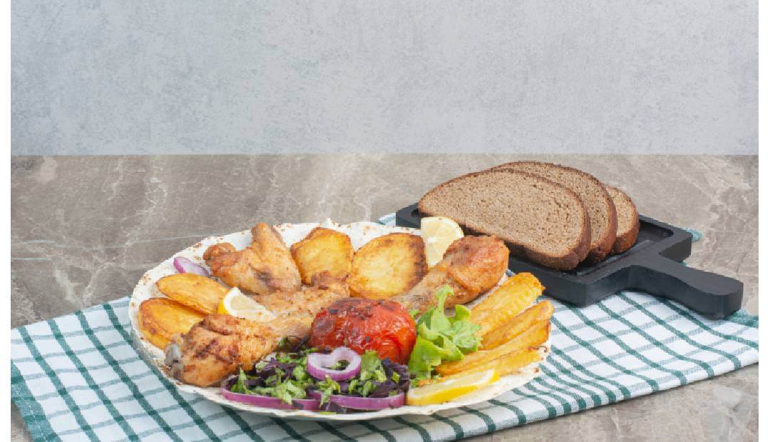 Crispy chicken wings and potatoes cooked in air fryer on serving plate